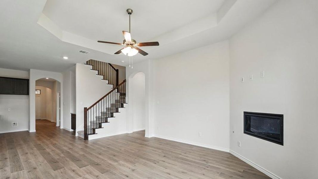 Spacious living area featuring wood-finish flooring, a recessed ceiling, and an integrated fireplace