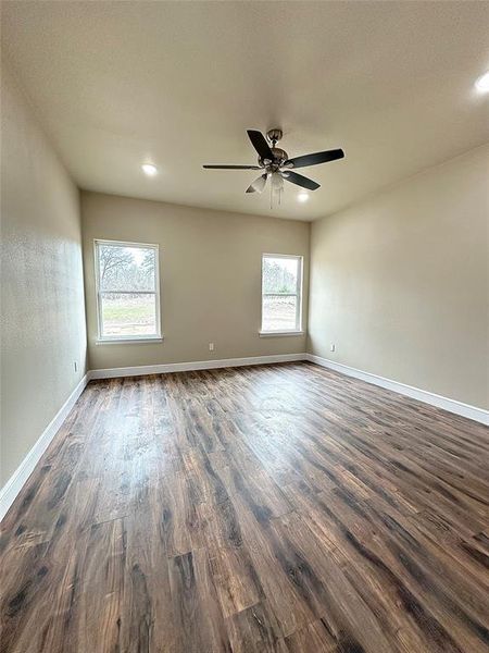 Empty room with ceiling fan and dark wood-type flooring