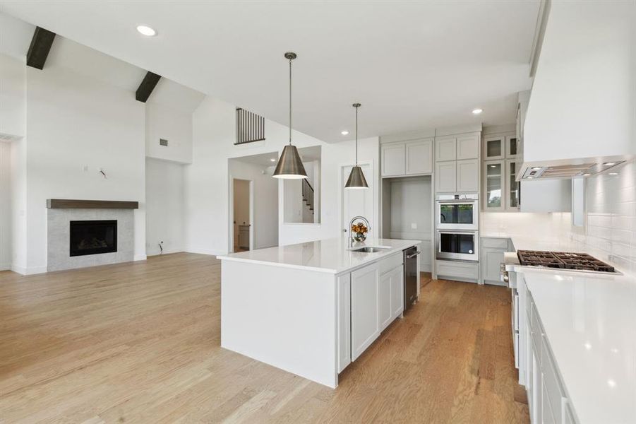 Open-concept kitchen and living area featuring high vaulted ceilings with exposed wood beams Open-concept kitchen and living area featuring high vaulted ceilings with exposed wood beams