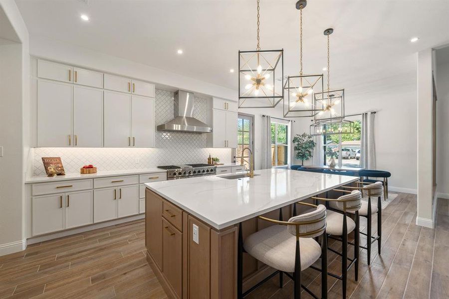 Kitchen with white cabinets, a kitchen breakfast bar, light wood-style flooring, backsplash, and recessed lighting Kitchen with white cabinets, a kitchen breakfast bar, light wood-style flooring, backsplash, and recessed lighting