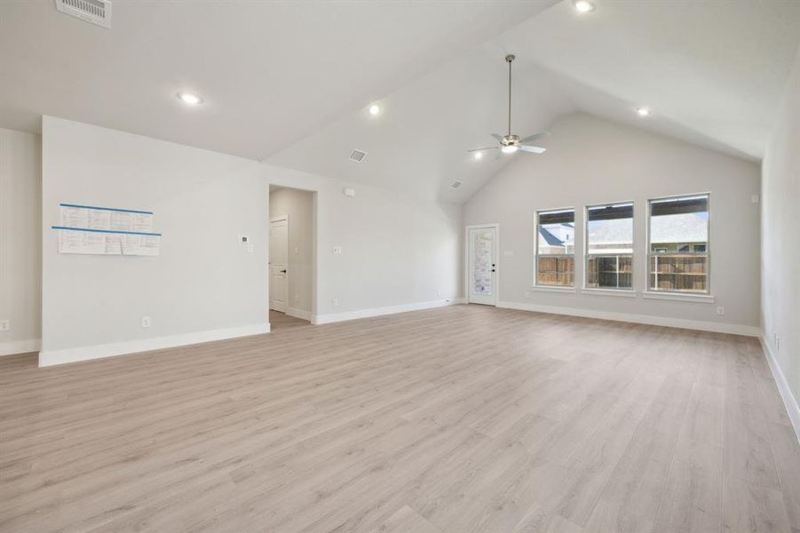 Unfurnished living room with ceiling fan, light hardwood / wood-style floors, and high vaulted ceiling