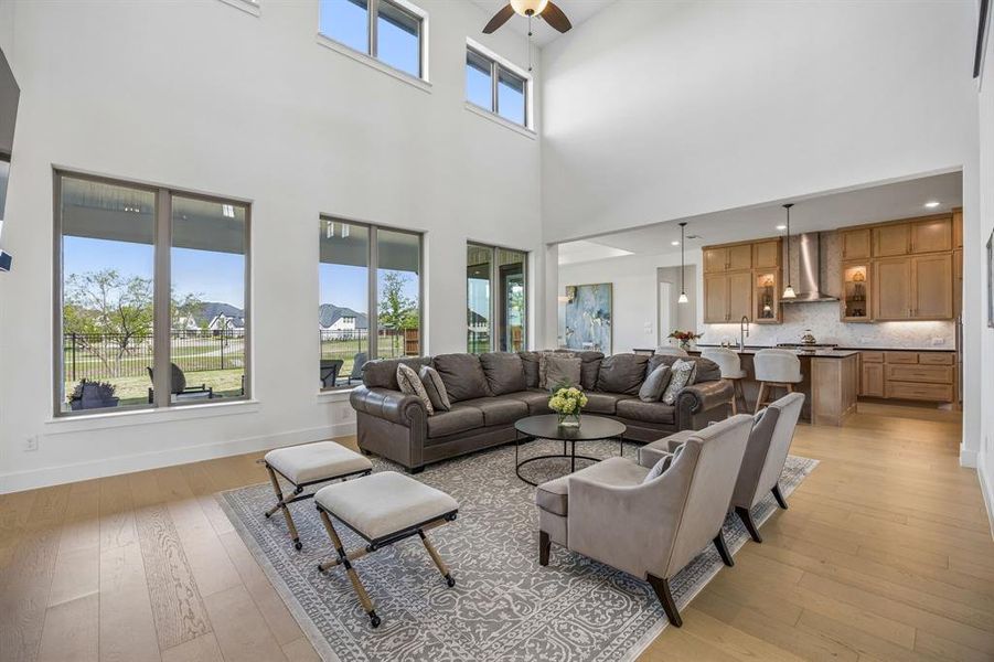 Living area with light wood-style floors, a ceiling fan, plenty of natural light, and a high ceiling