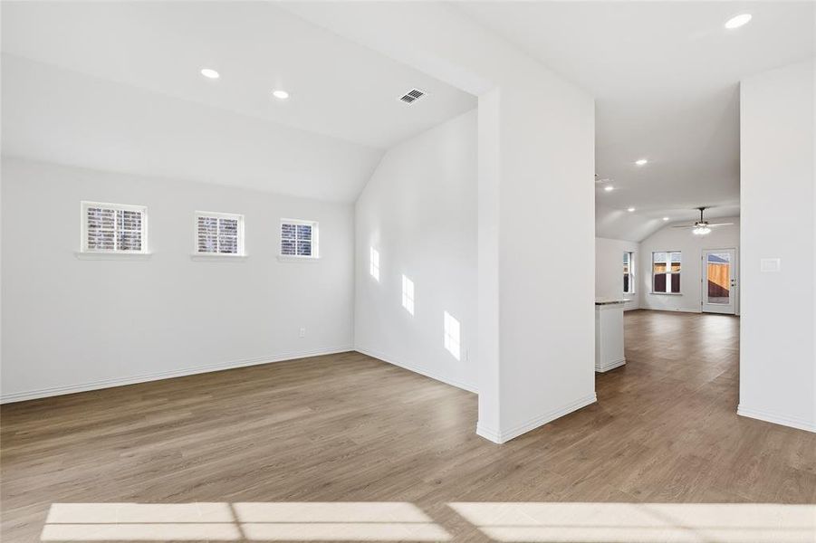 Empty room featuring vaulted ceiling, light wood finished floors, recessed lighting, and a ceiling fan Empty room featuring vaulted ceiling, light wood finished floors, recessed lighting, and a ceiling fan