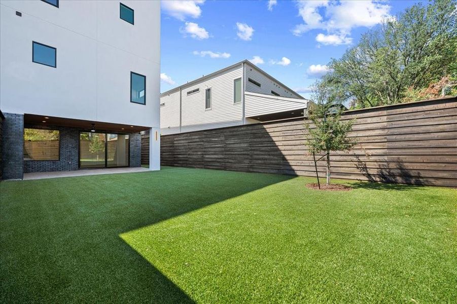 Fenced backyard featuring a patio area & artificial grass Fenced backyard featuring a patio area & artificial grass
