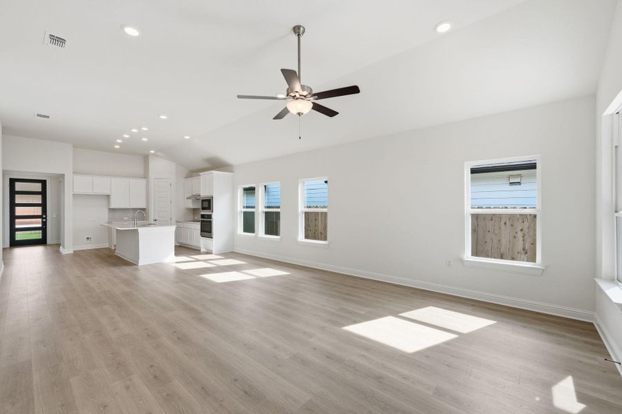 Unfurnished living room with lofted ceiling, light wood-style flooring, recessed lighting, and a ceiling fan Unfurnished living room with lofted ceiling, light wood-style flooring, recessed lighting, and a ceiling fan
