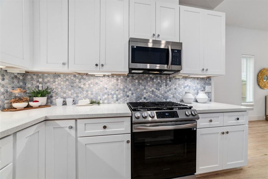 Quartz Countertops, A Waterfall Island, Modern White Cabinetry With Lighting, Undermount Sink And Gorgeous Mosaic Backsplash Wrap Around This Contemporary Kitchen