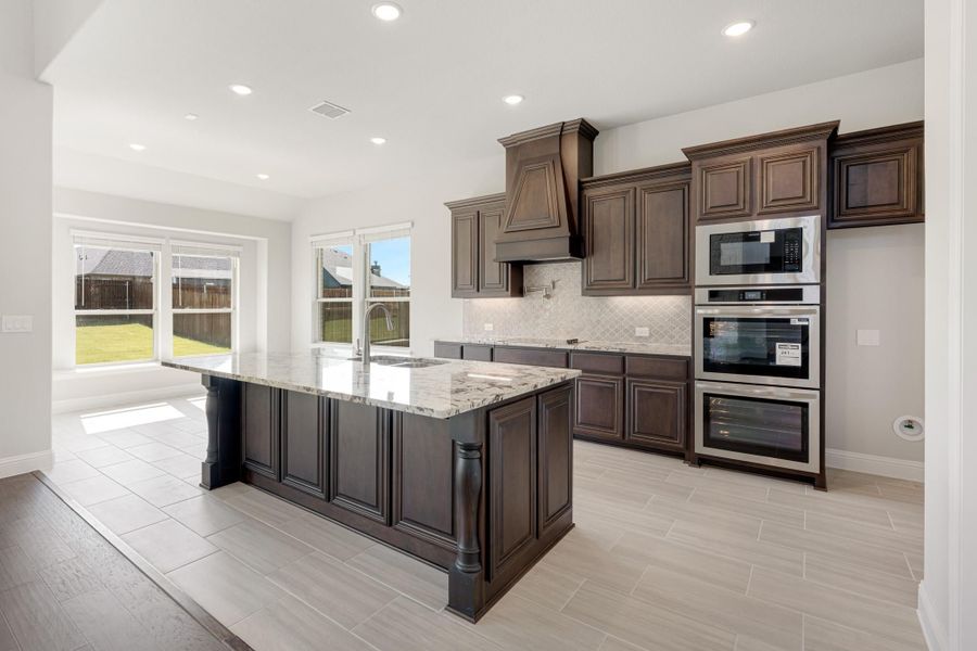 Kitchen with dark wood cabinets, granite island, stainless steel appliances, and tile floors Kitchen with dark wood cabinets, granite island, stainless steel appliances, and tile floors