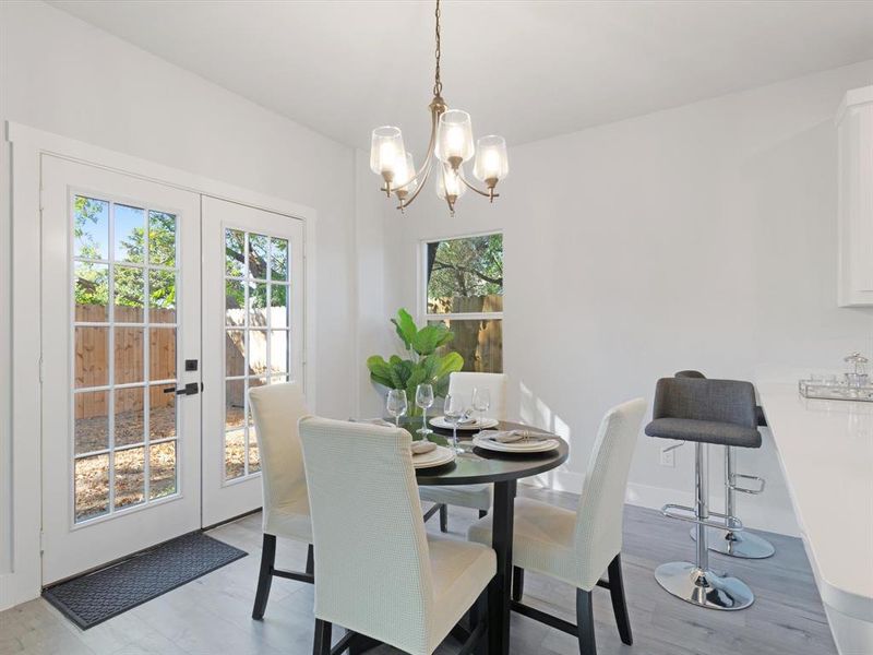 Dining area with an inviting chandelier, light wood-type flooring, and french doors