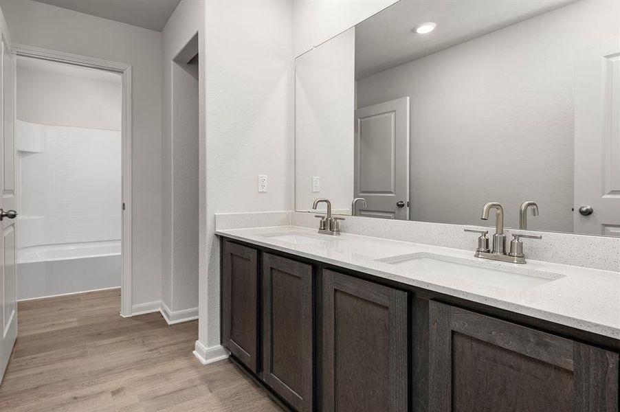 Bathroom with double vanity, light wood-style floors, and washtub / shower combination
