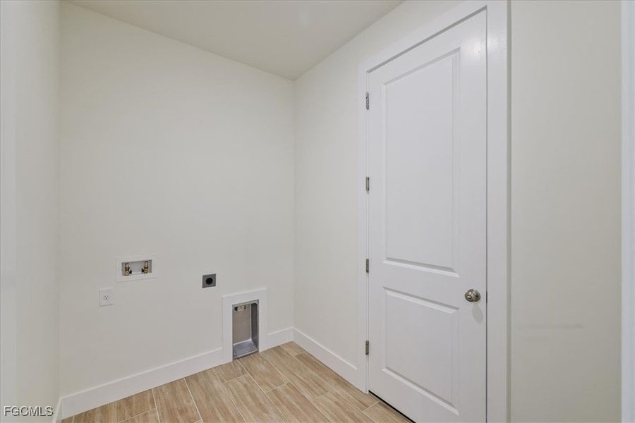 Washroom with wood finish floors, hookup for an electric dryer, and washer hookup