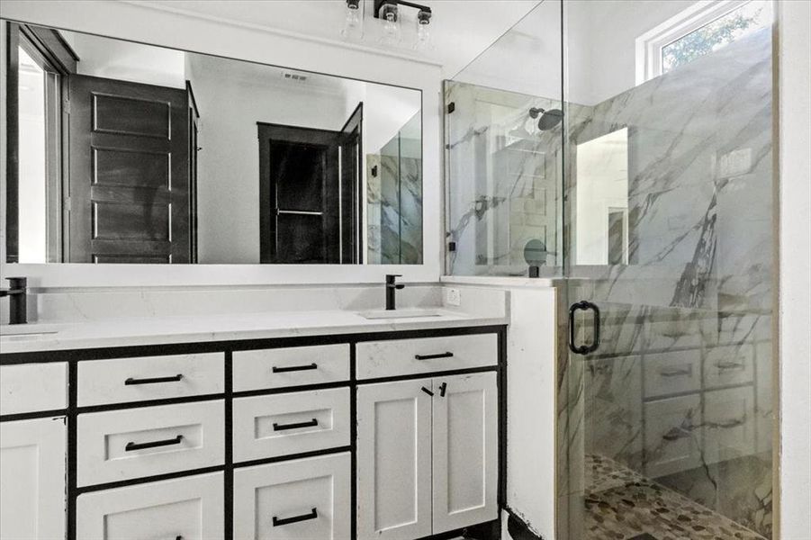Bathroom featuring a marble finish shower and double vanity