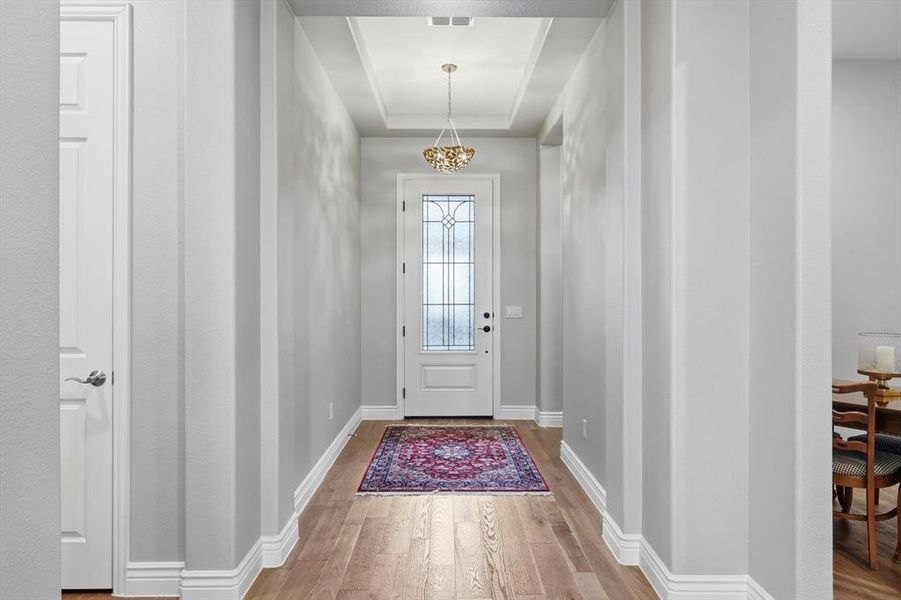 Grand Entry with Coffered Ceilings, Warm Paint Shades, and Honey-toned Engineered Italian Hardwood Floors that Extend Throughout the Main Living Areas..