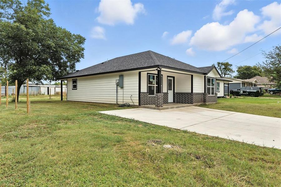 View of home's exterior with brick siding, roof with shingles, concrete driveway, and a lawn View of home's exterior with brick siding, roof with shingles, concrete driveway, and a lawn