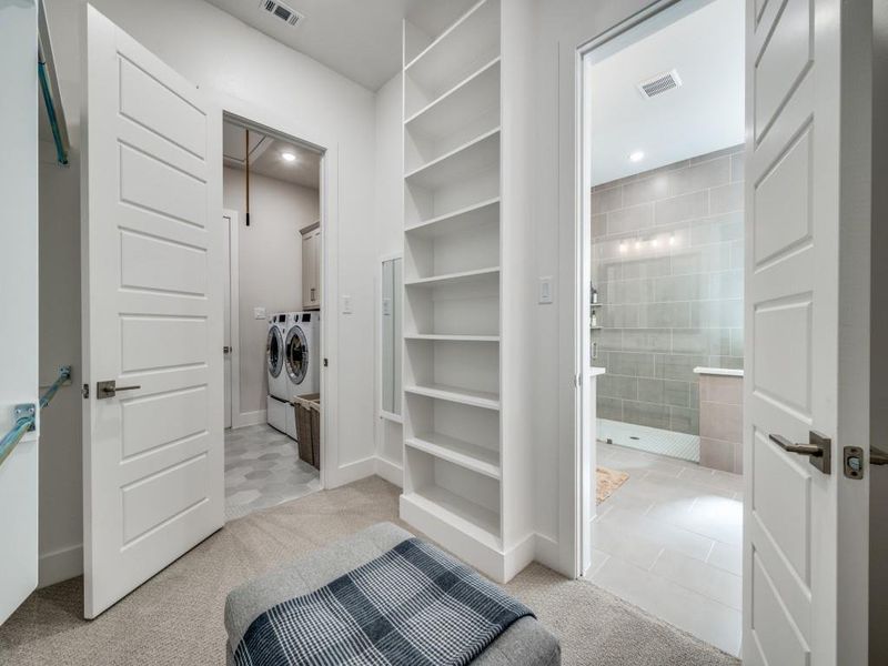 Walk in closet with separate washer and dryer and light colored carpet