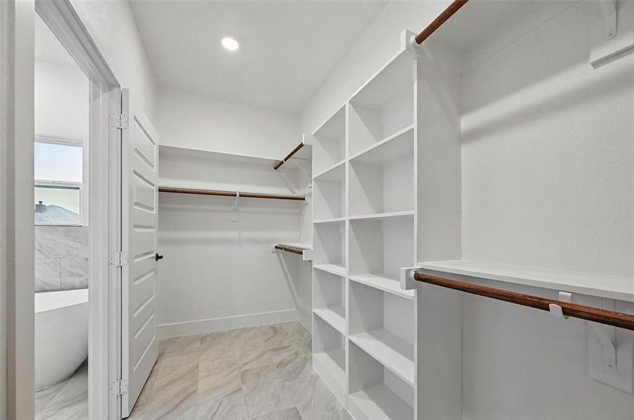 Spacious closet featuring light marble finish flooring