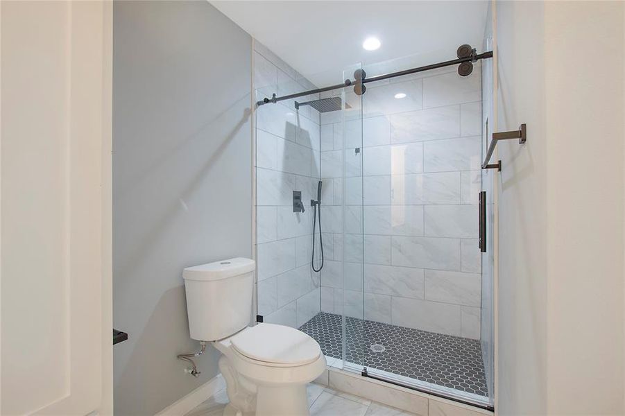 Bathroom featuring tile patterned flooring, a shower with shower door, and toilet