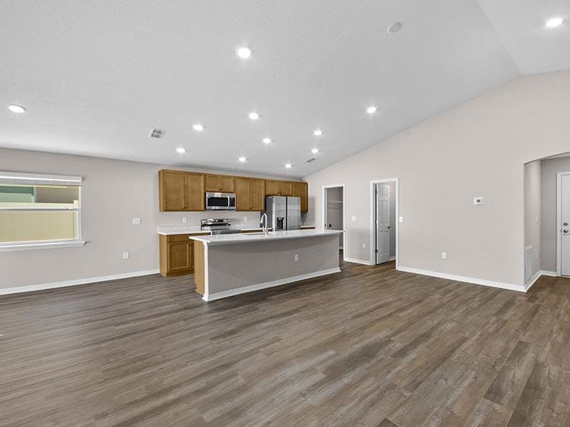 This sunny, open-concept home features an airy volume ceiling with luxury vinyl plank flooring.