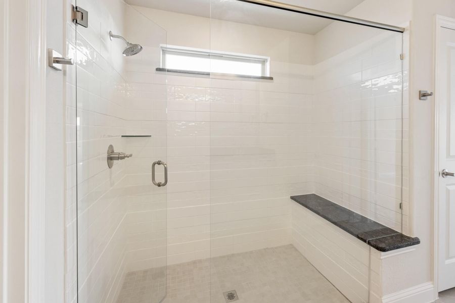 Walk-in shower with white tile walls, glass door, built-in bench, and small window Walk-in shower with white tile walls, glass door, built-in bench, and small window
