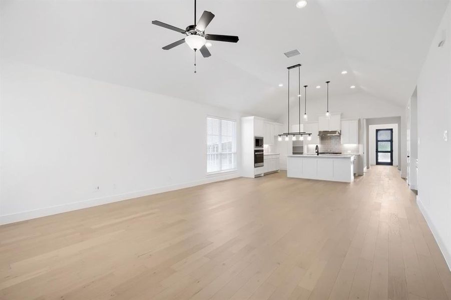 Open-concept living space featuring light wood-finish flooring and a vaulted ceiling