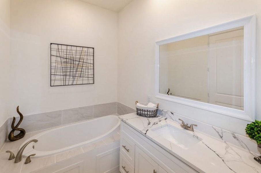 Bathroom featuring tiled bath and vanity