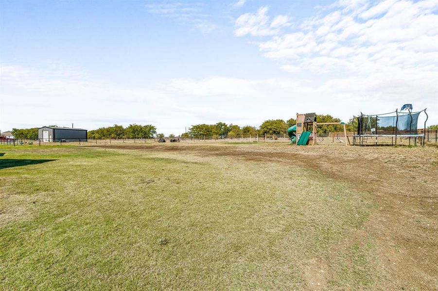 Community play area featuring a trampoline and a rural view