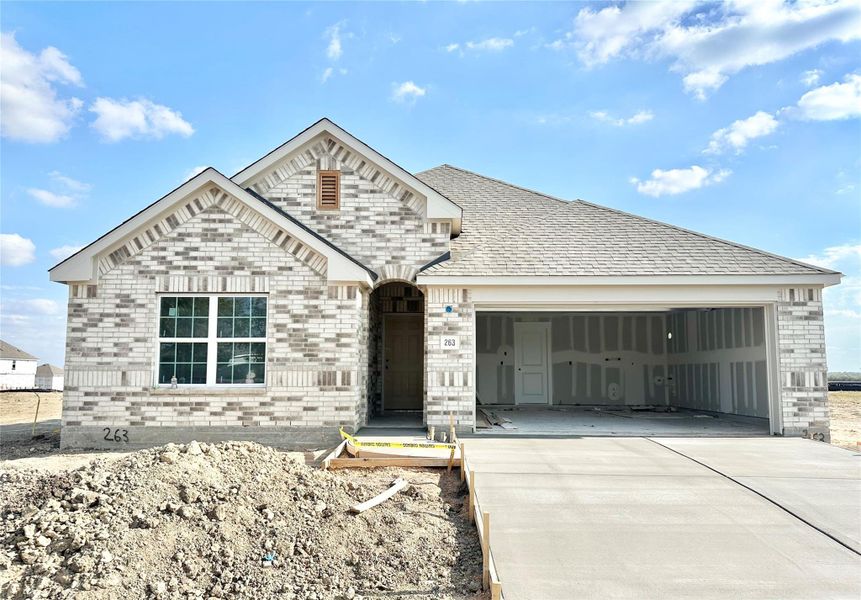 View of front of home with brick siding, concrete driveway, and an attached garage