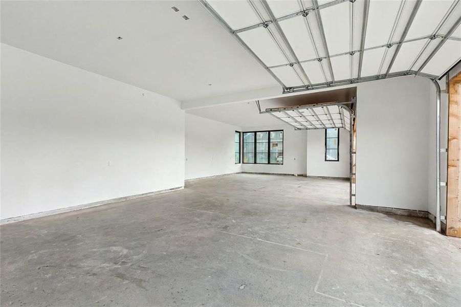 Spacious garage with exposed concrete flooring, white painted walls, and a visible garage door mechanism