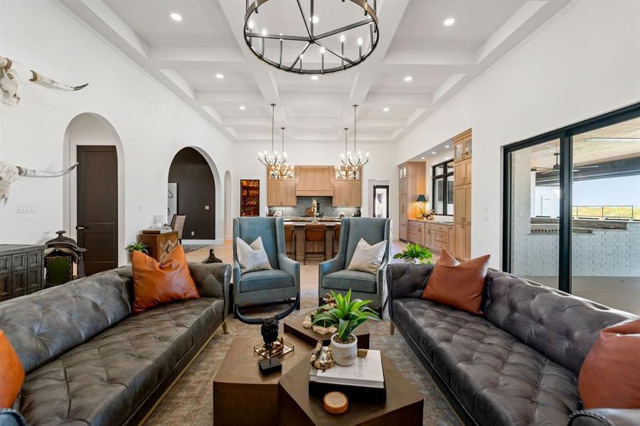 Living area featuring a high ceiling, a chandelier, coffered ceiling, beamed ceiling, and arched walkways Living area featuring a high ceiling, a chandelier, coffered ceiling, beamed ceiling, and arched walkways