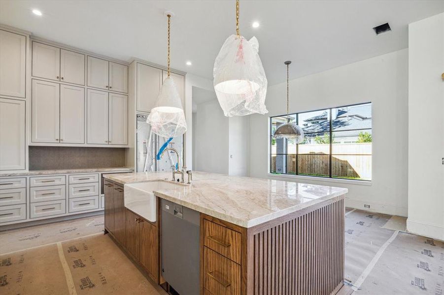 Another view of the kitchen featuring a farm sink, dishwasher to be paneled to match the island finish. Brizo plumbing fixtures complement this elegant kitchen. Note the kitchen cabinetry extended to the ceiling and the extra storage space it provides.