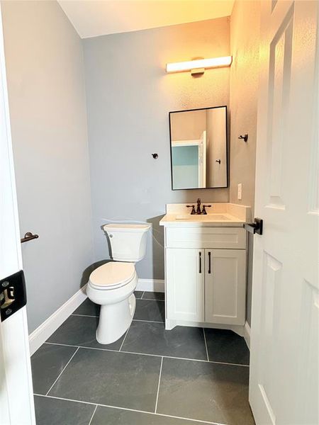 Bathroom featuring a white vanity with cabinet storage, a rectangular sink, and a black-framed mirror