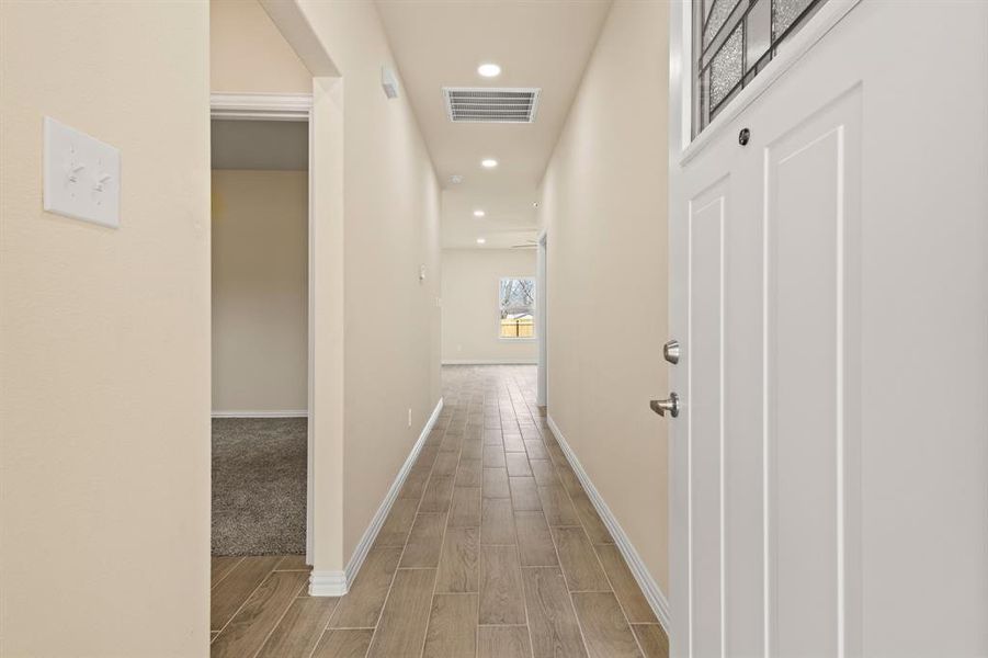 Corridor featuring wood finish floors, visible vents, baseboards, and recessed lighting