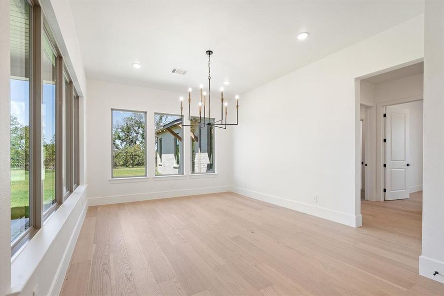 Unfurnished dining area with a chandelier and light hardwood / wood-style flooring