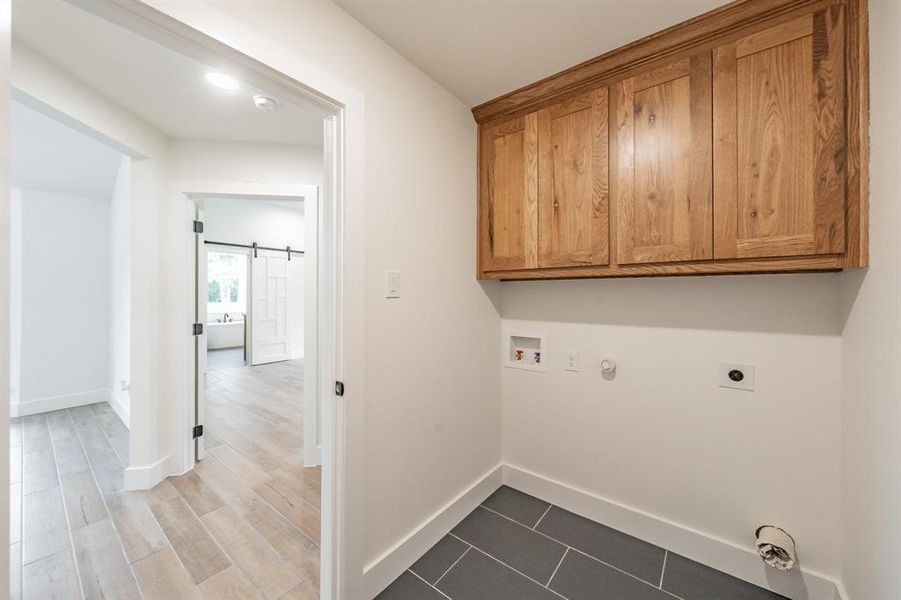 Washroom with cabinet space, a barn door, washer hookup, baseboards, and gas dryer hookup