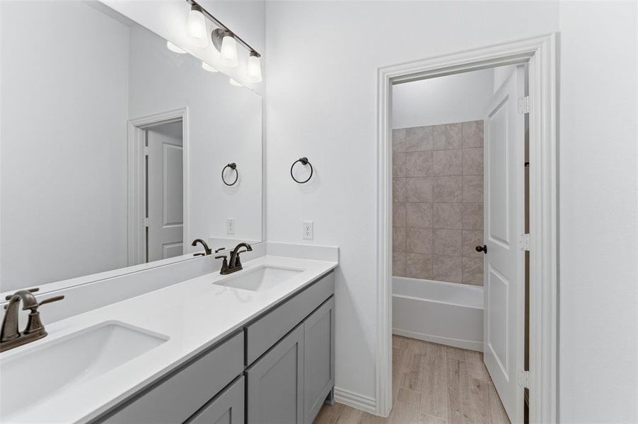 Bathroom featuring a double vanity with gray cabinetry, white countertops, and bronze fixtures
