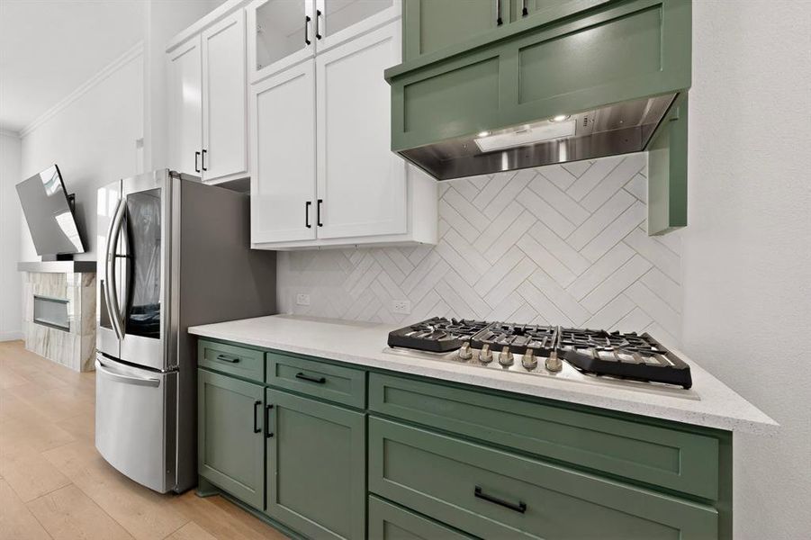 Kitchen featuring two-tone cabinetry with white upper cabinets and green lower cabinets, complemented by a white herringbone tile backsplash Kitchen featuring two-tone cabinetry with white upper cabinets and green lower cabinets, complemented by a white herringbone tile backsplash