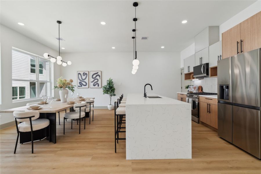 Clean lines, vertical cabinetry, and mixed wood tones evoke a Scandinavian-inspired sophistication, blending style with function.