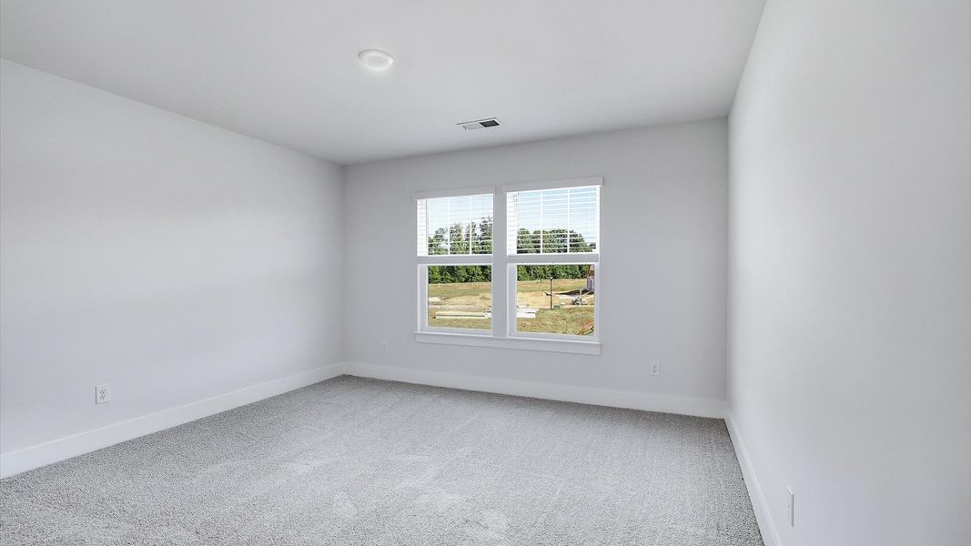 Highly functional bedroom with large windows, carpeted flooring, and tasteful finishes throughout by DRB Homes