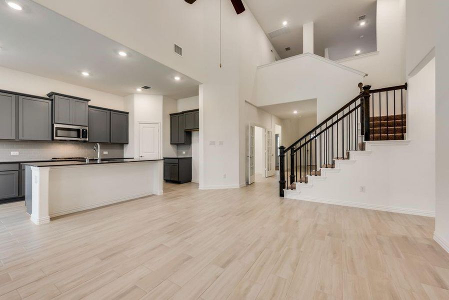 Kitchen with ceiling fan, gray cabinetry, a center island with sink, light hardwood / wood-style flooring, and a high ceiling