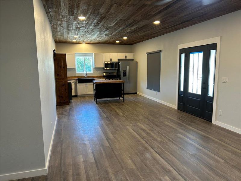 Kitchen featuring white cabinetry, stainless steel appliances, dark wood-style flooring, and wooden ceiling Kitchen featuring white cabinetry, stainless steel appliances, dark wood-style flooring, and wooden ceiling