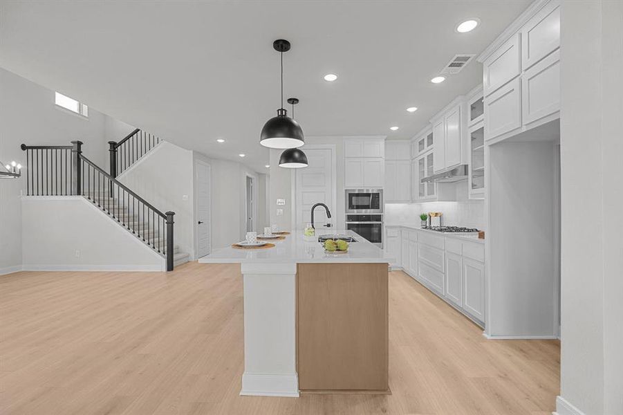 Modern kitchen featuring a light wood-finish flooring, white cabinetry, a built-in oven and microwave, and a gas cooktop Modern kitchen featuring a light wood-finish flooring, white cabinetry, a built-in oven and microwave, and a gas cooktop