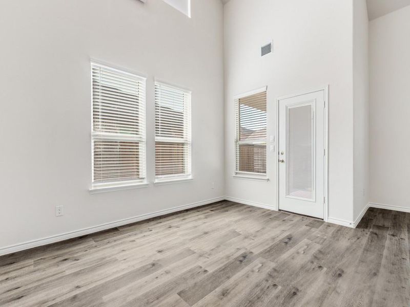 Unfurnished room featuring light wood-type flooring and a high ceiling