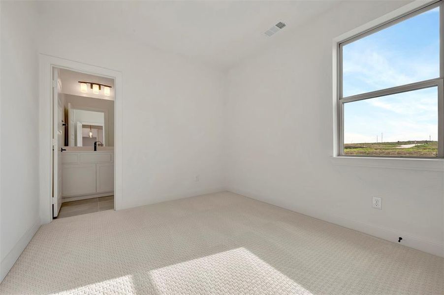 Unfurnished bedroom with light colored carpet and ensuite bathroom