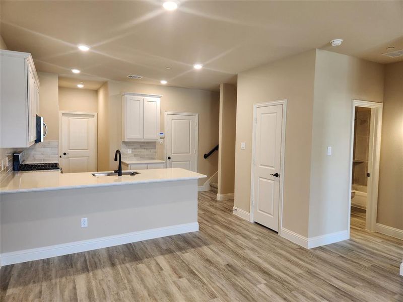 Kitchen featuring light hardwood / wood-style flooring, white cabinets, backsplash, stove, and sink