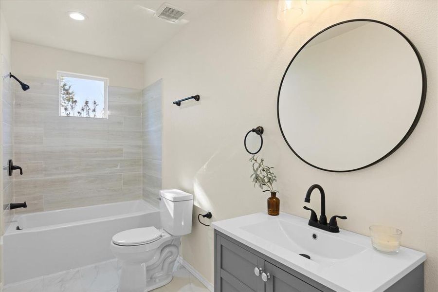 Full bathroom with tiled shower / bath combo, vanity, and toilet