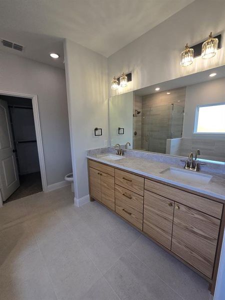 Bathroom with double vanity, a stall shower, recessed lighting, a spacious closet, and light tile patterned flooring