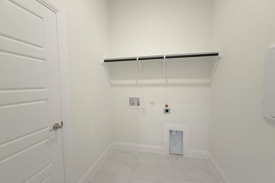 Dedicated laundry area featuring white tile flooring, built-in shelving, and a panel door Dedicated laundry area featuring white tile flooring, built-in shelving, and a panel door