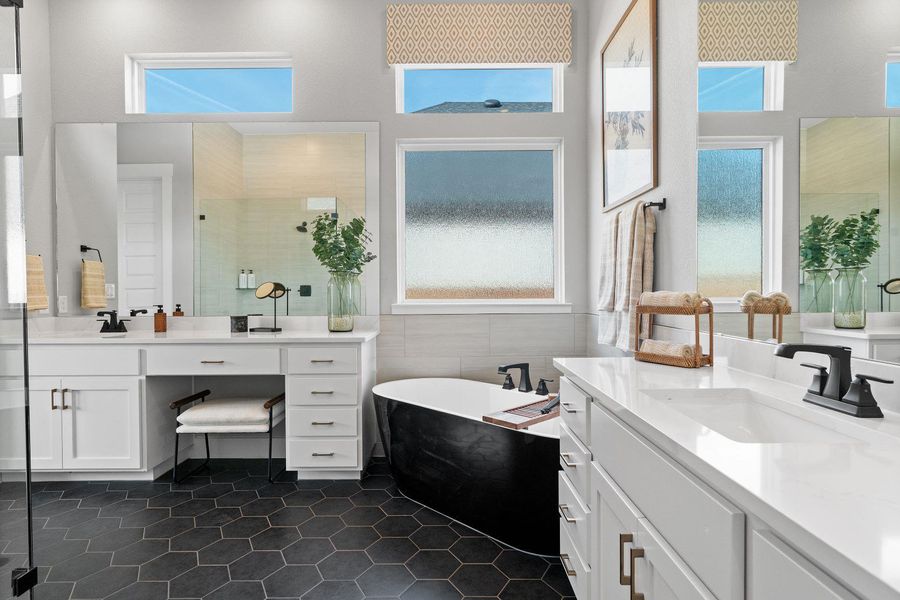 Black hexagonal tile flooring grounds this airy bathroom, featuring a freestanding tub and double vanity with quartz countertops. Black hexagonal tile flooring grounds this airy bathroom, featuring a freestanding tub and double vanity with quartz countertops.