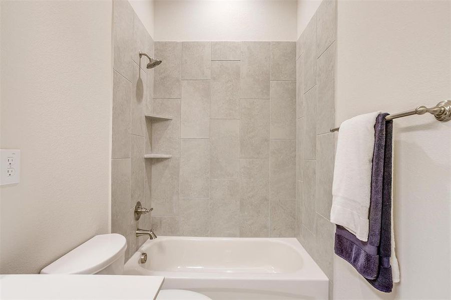 Bathroom with toilet and tiled shower / bath