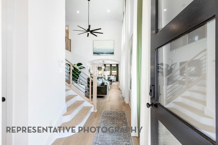 Entryway featuring wood finished floors, arched walkways, stairs, ceiling fan, and a high ceiling Entryway featuring wood finished floors, arched walkways, stairs, ceiling fan, and a high ceiling