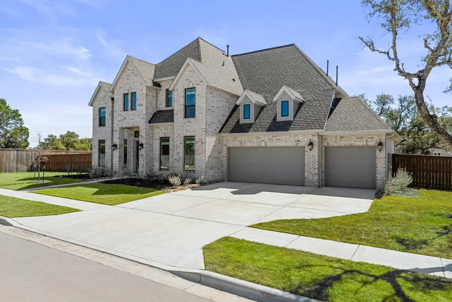 French provincial home with a garage, a shingled roof, fence, a front lawn, and brick siding